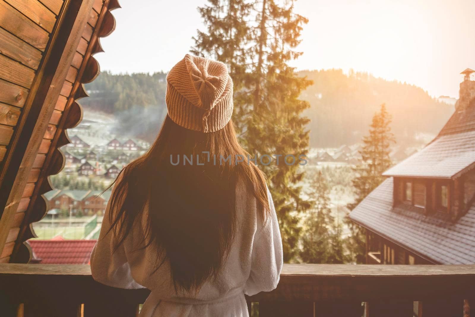 The girl is standing on a terraced house in a mountainous area. In good winter weather.