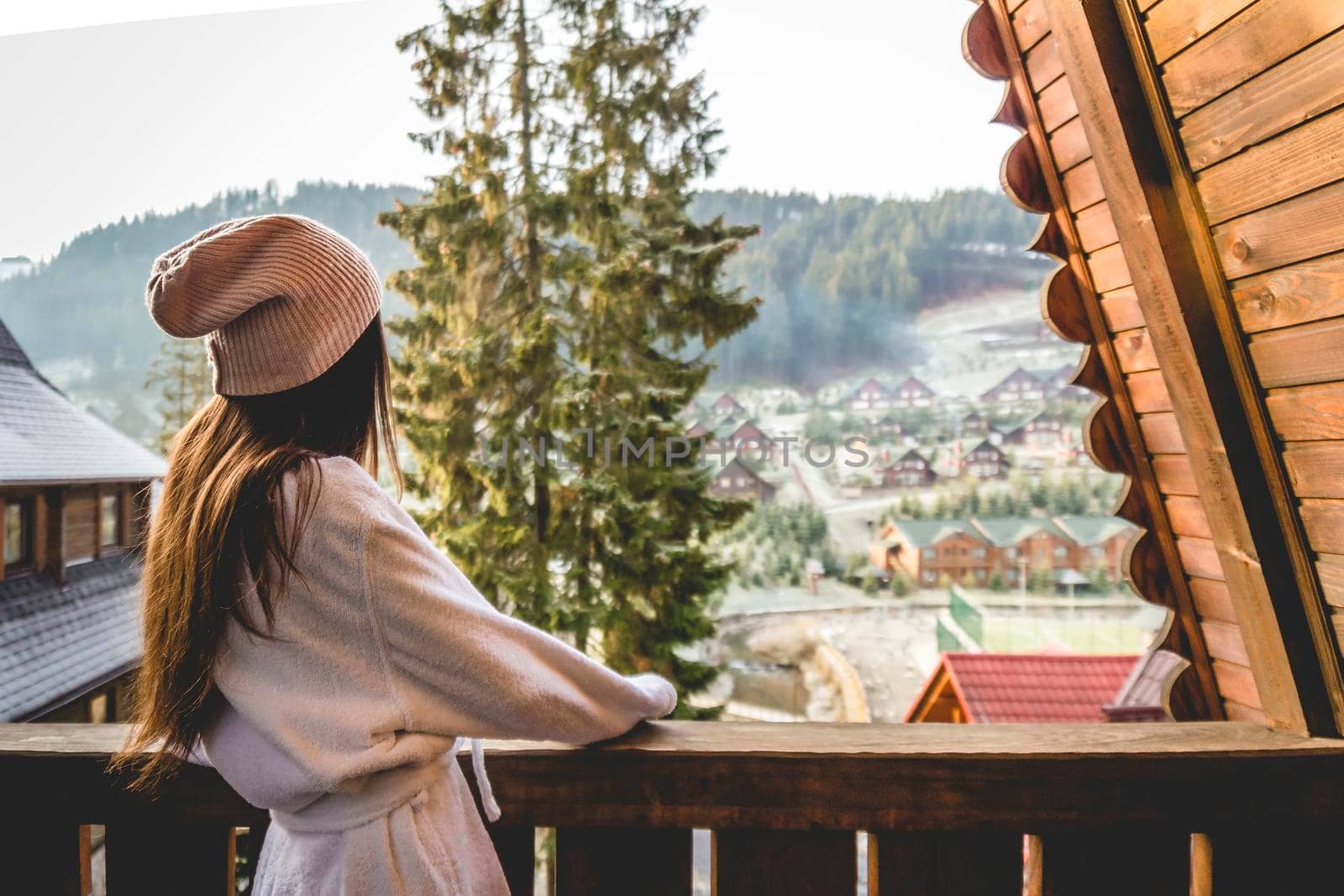 The girl is standing on a terraced house in a mountainous area. In good winter weather.