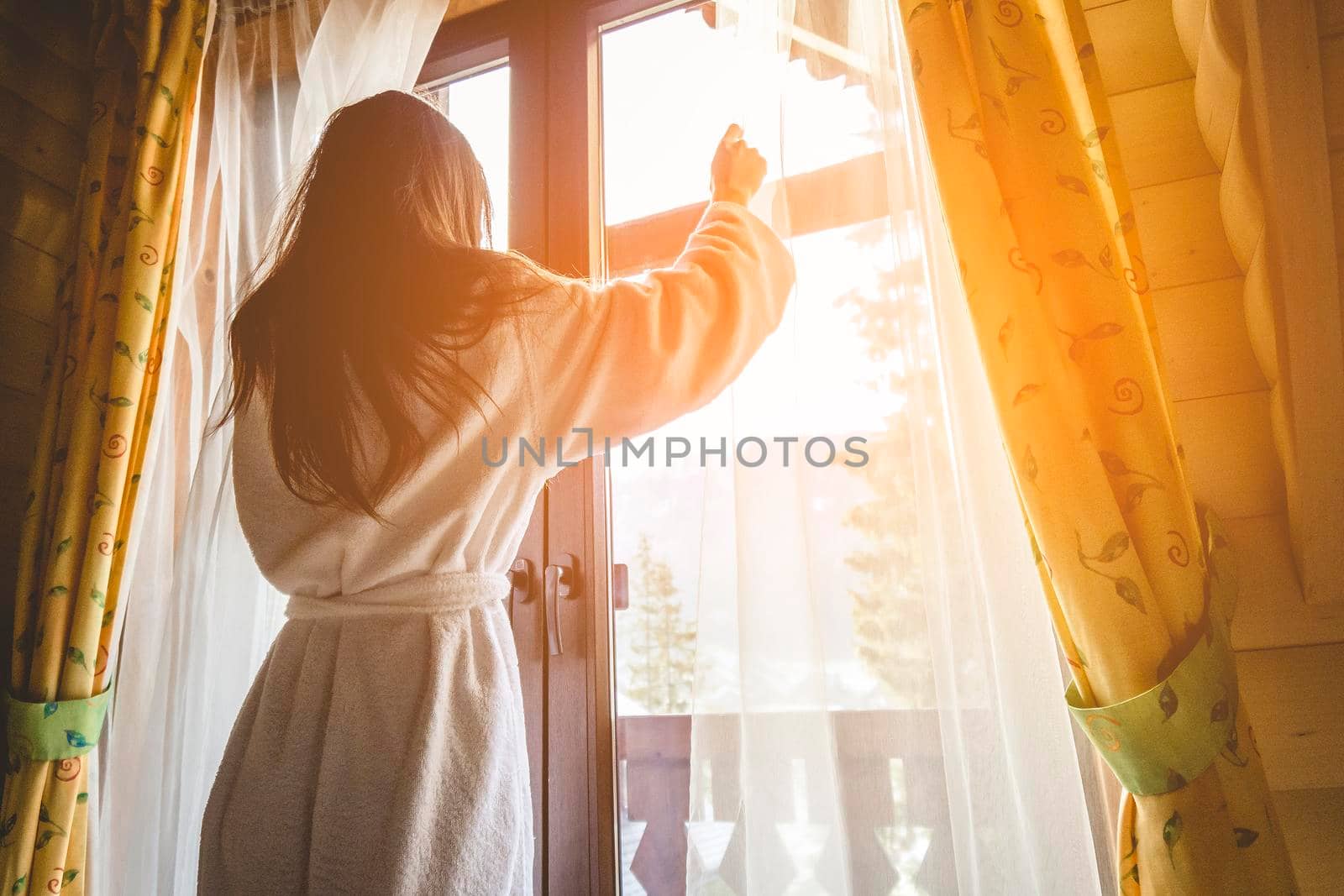 The girl is standing on a terraced house in a mountainous area. In good winter weather.