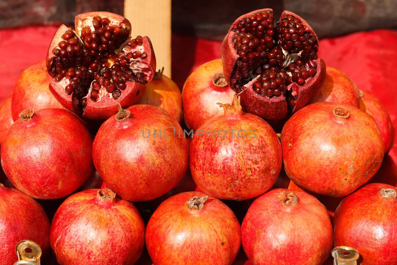 Several ripe pomegranates and an open pomegranate are lined up on a market stall. selective focus by lara29