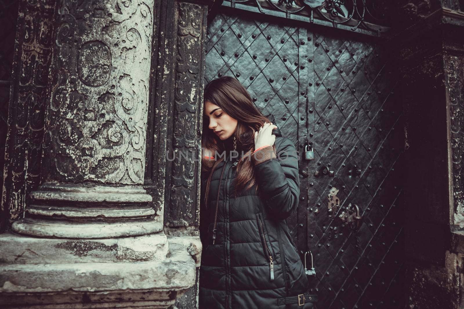 The young girl stands on the background of the old gothic wall.