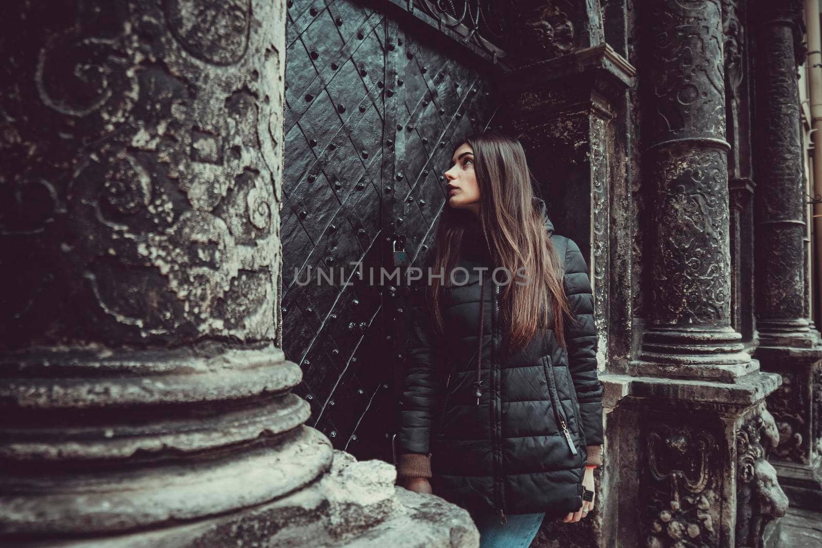 The young girl stands on the background of the old gothic wall.