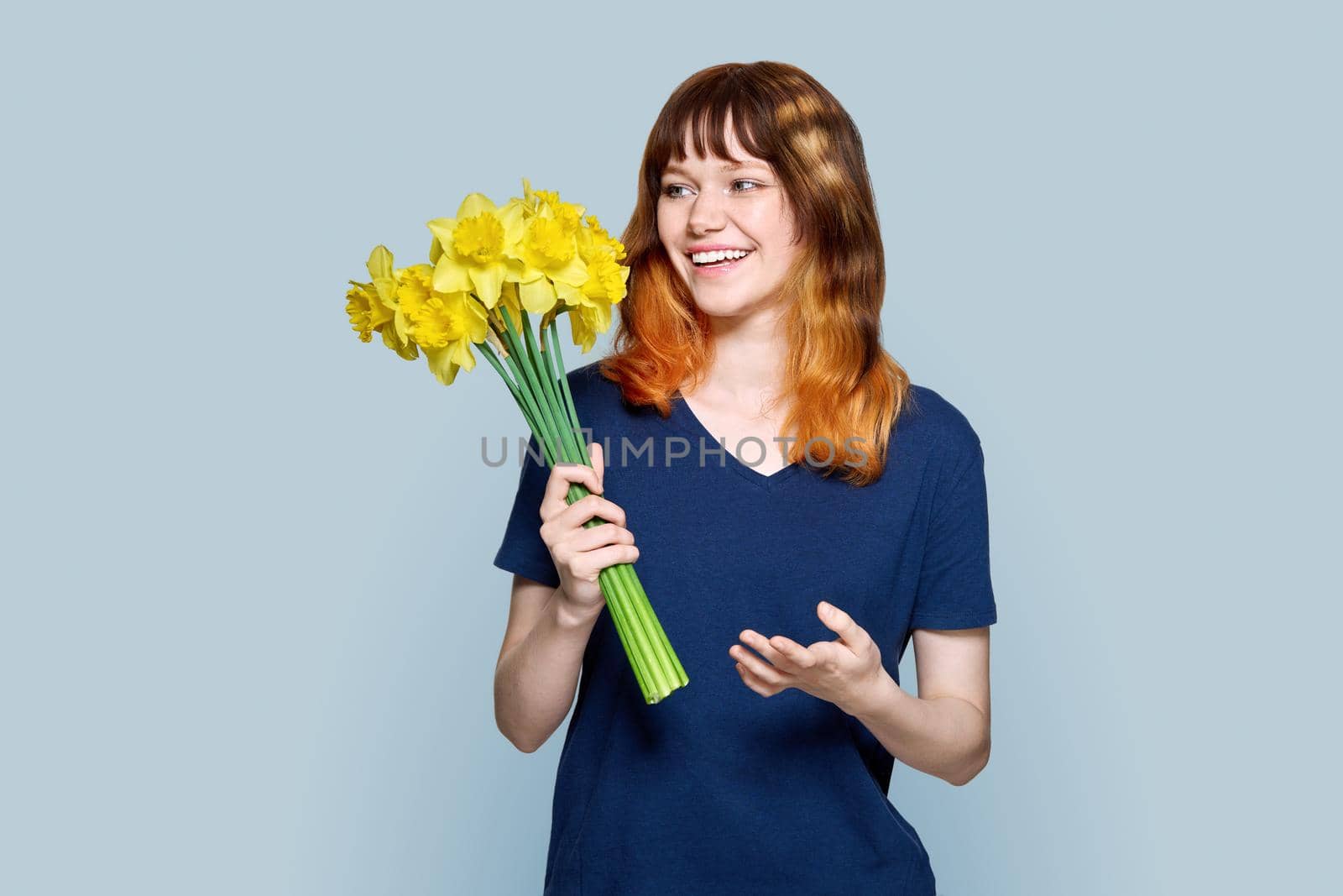 Young female with bouquet of yellow flowers on gray background by VH-studio