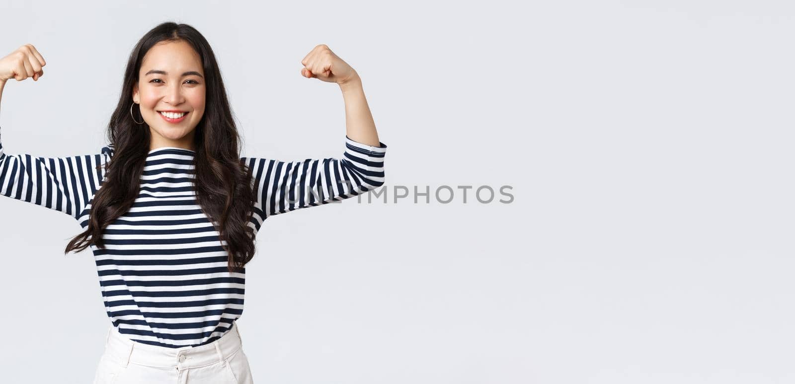 Lifestyle, people emotions and casual concept. Strong and confident asian woman flex biceps, bragging her perfect shape after sign-up gym membership, brag with muscles, workout and feeling strong.