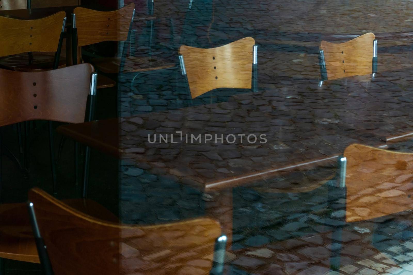 Wooden chairs and tables behind the glass wall of a closed bar