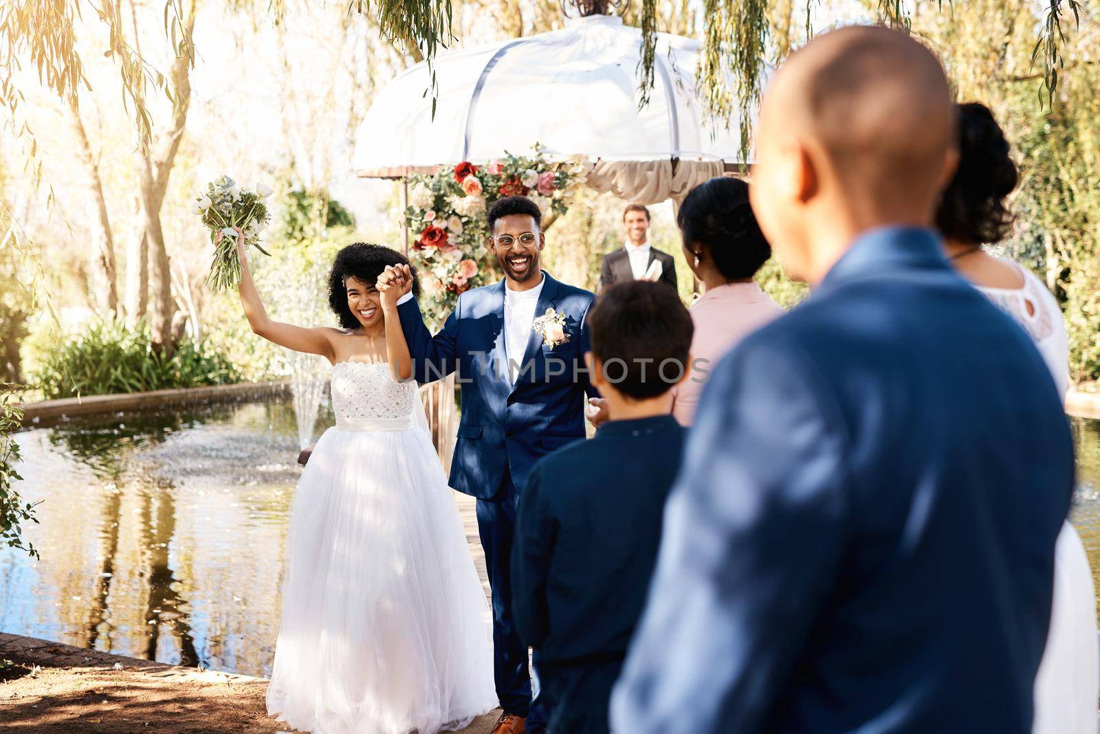 The power of love has brought us all here today. a happy newlywed young couple walking down the aisle in front guests on their wedding day. by YuriArcurs