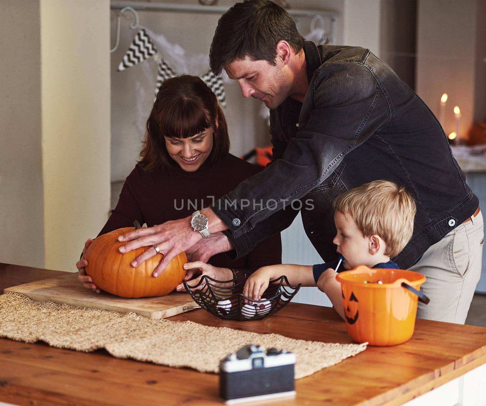 Were getting into the spirit of halloween. an adorable young family carving out pumpkins and celebrating halloween together at home. by YuriArcurs