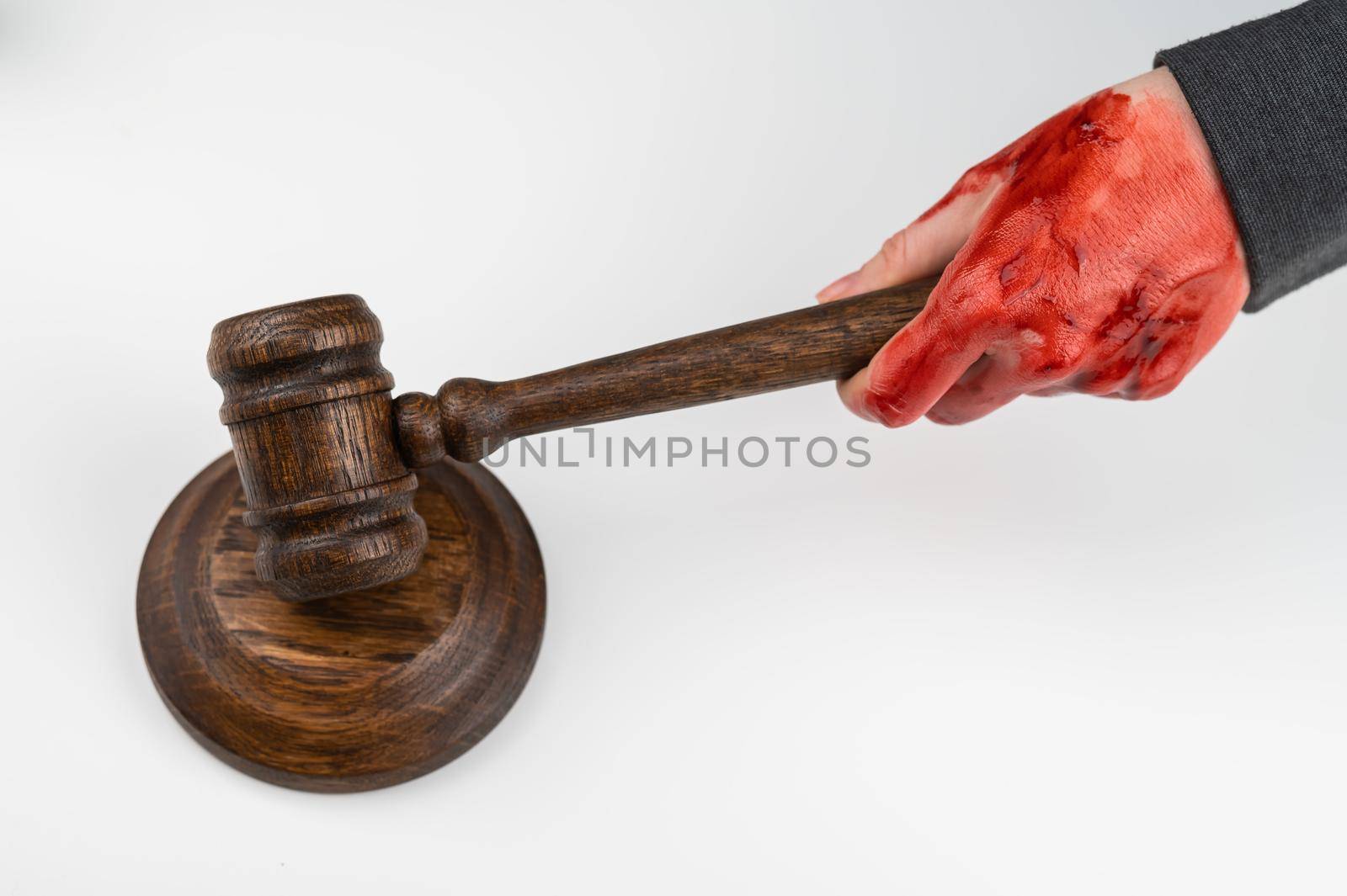 Female judge with bloody hands beats the gavel on a white background. by mrwed54