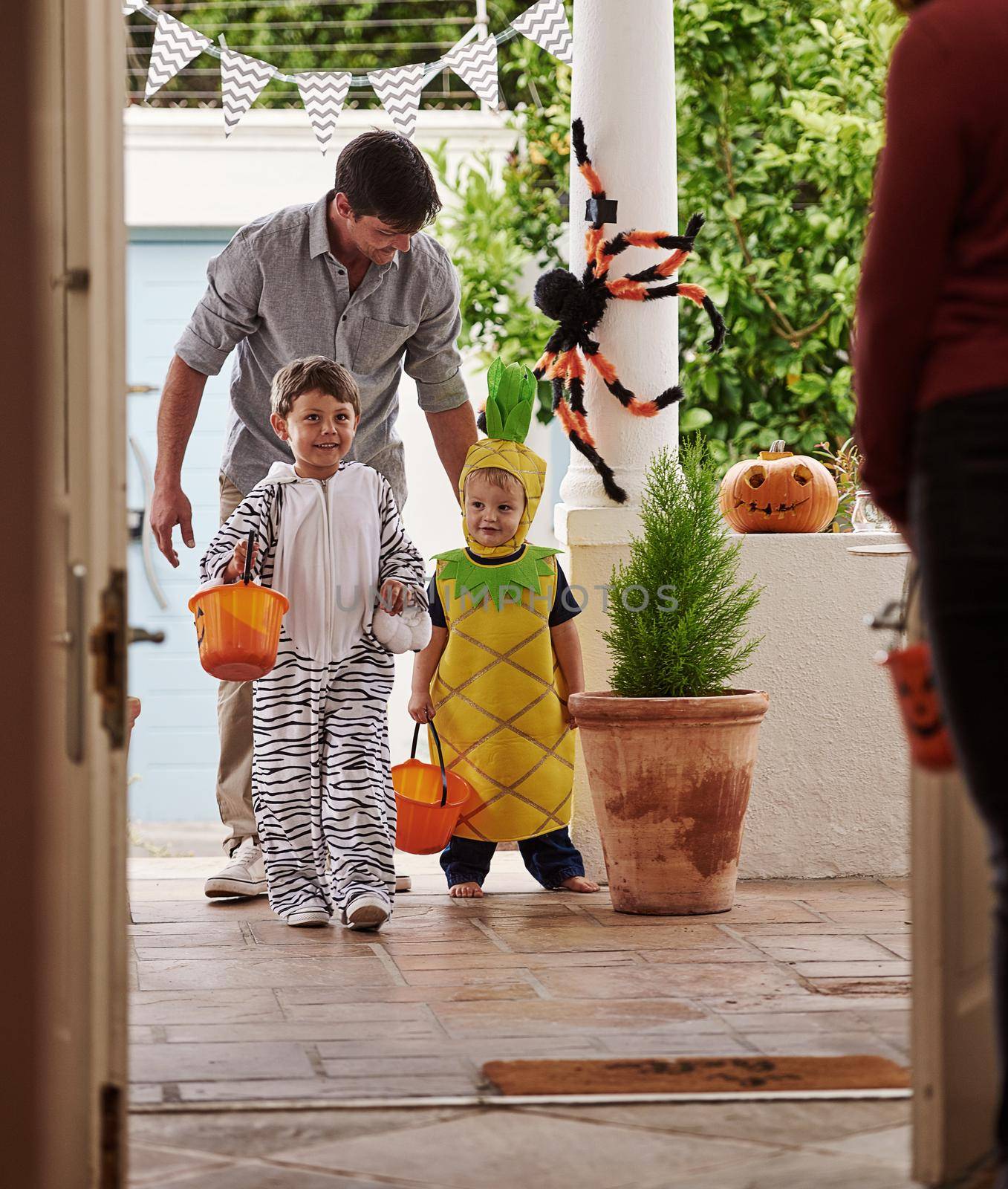 Halloween is always a real treat. Full length shot of a father and his adorable young sons trick or treating together on halloween. by YuriArcurs