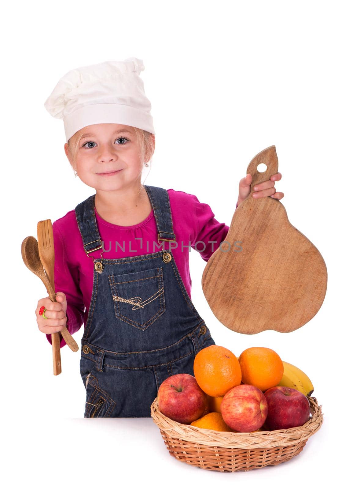 Close-up portrait of a little girl holding fruits - apples, bananas and oranges and kitchen appliances. Isolated on a light background. by aprilphoto