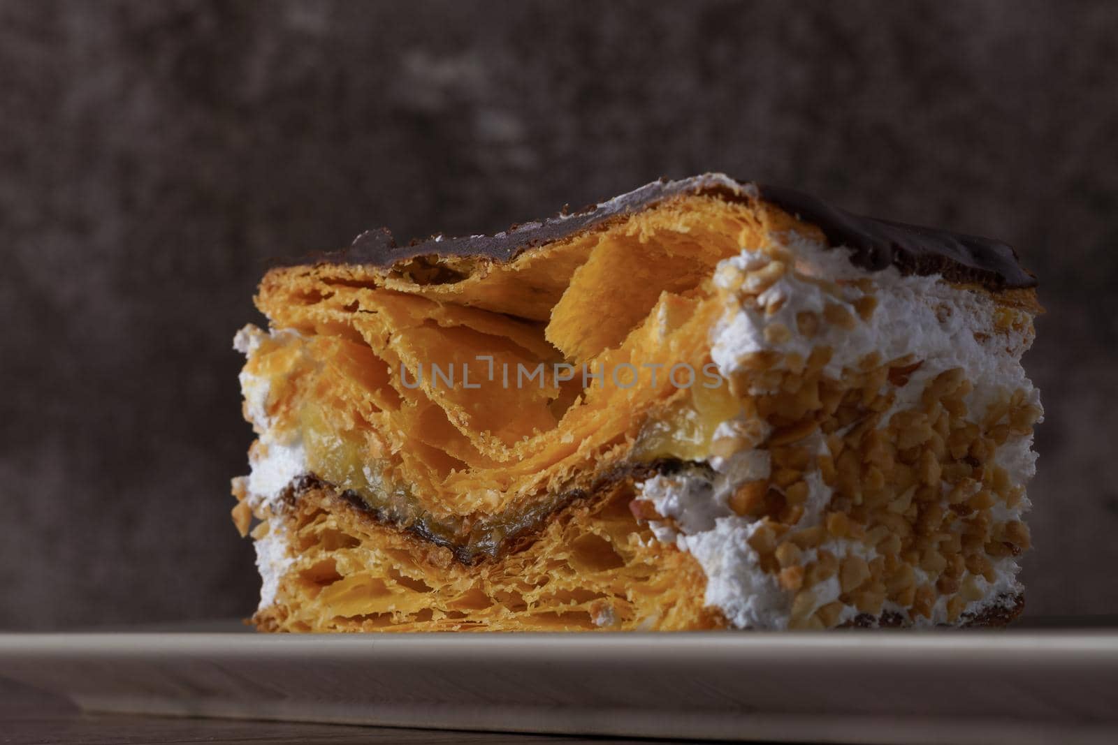 close-up of a chocolate-covered puff pastry with cream and almonds by joseantona