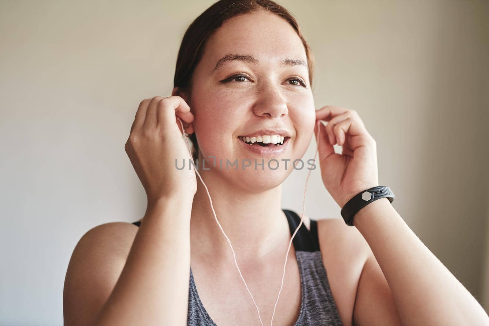 Music ready, lets go. an attractive young woman standing alone and listening to music through earphones before her workout at home. by YuriArcurs