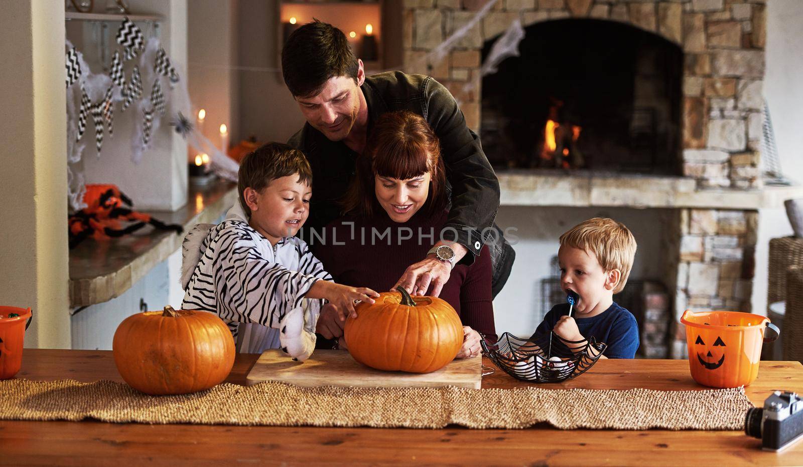 Things are getting really spooky right now. an adorable young family carving out pumpkins and celebrating halloween together at home. by YuriArcurs