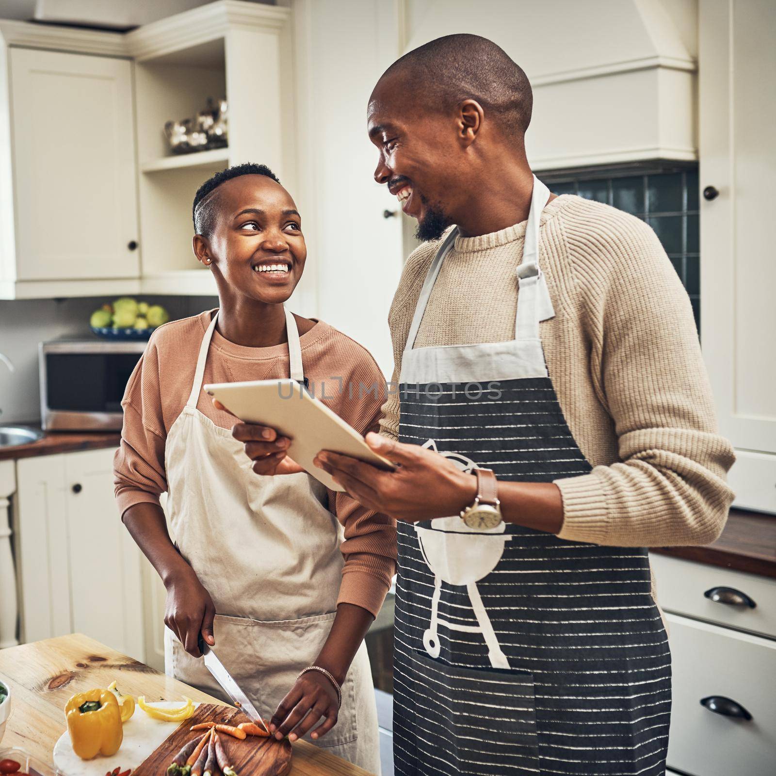 What does the recipe say. an affectionate young couple using a tablet while preparing dinner in their kitchen