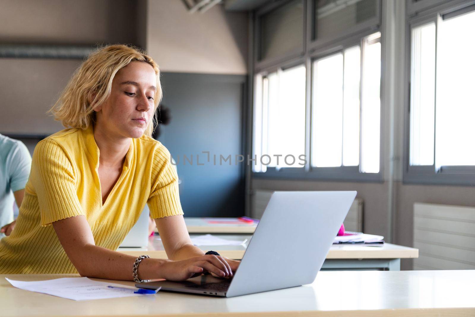 Caucasian blonde female teen high school student using laptop in class. Copy space. Education concept. Back to school.