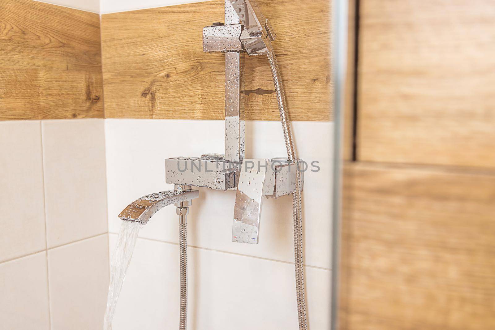 Close-up of plumbing equipment. New, clean, chrome, shower and small faucet on a white wall, copy and paste your design. the concept of hygiene and clean home, room cleaning