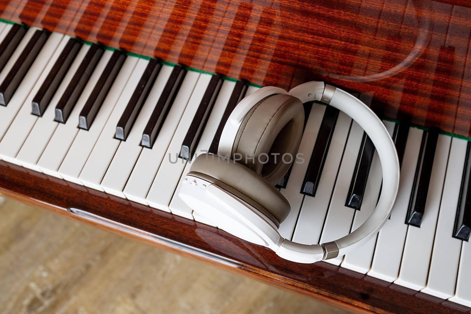 Close-up, white headphones lie on the piano keys. View from above by Ramanouskaya