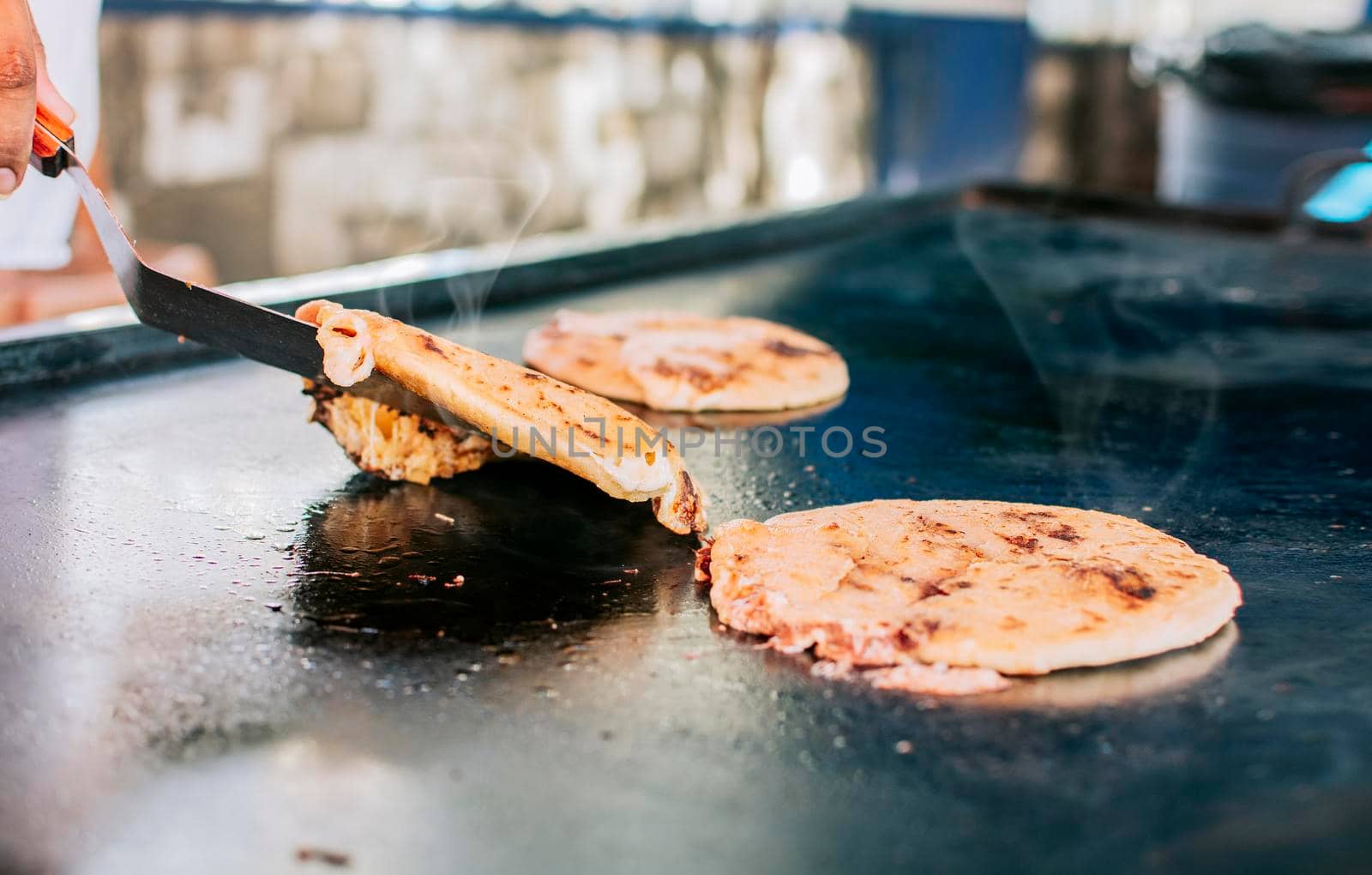 Spatula taking a traditional cheese pupusas on the grill, Close up of traditional artisan grilled pupusas. Traditional Nicaraguan pupusas with melted grilled cheese