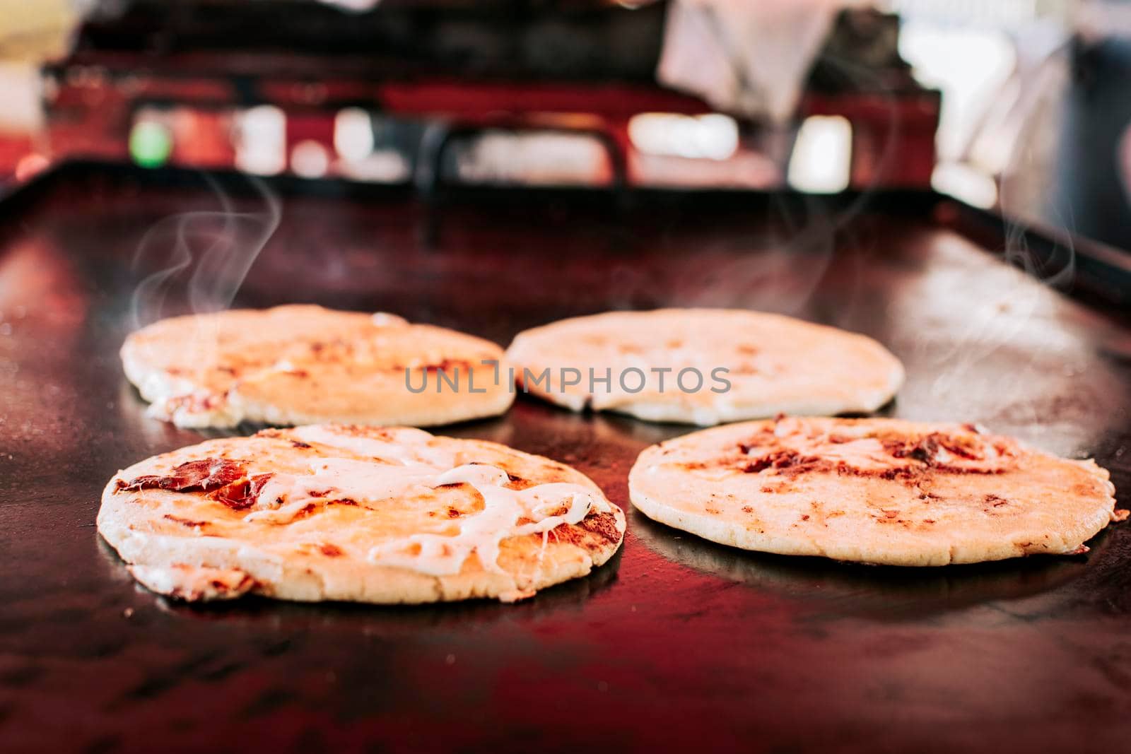 Traditional Salvadoran pupusas with melted cheese on a grill, Traditional cheese pupusas on the grill. Side view of four traditional crispy pupusas on the grill
