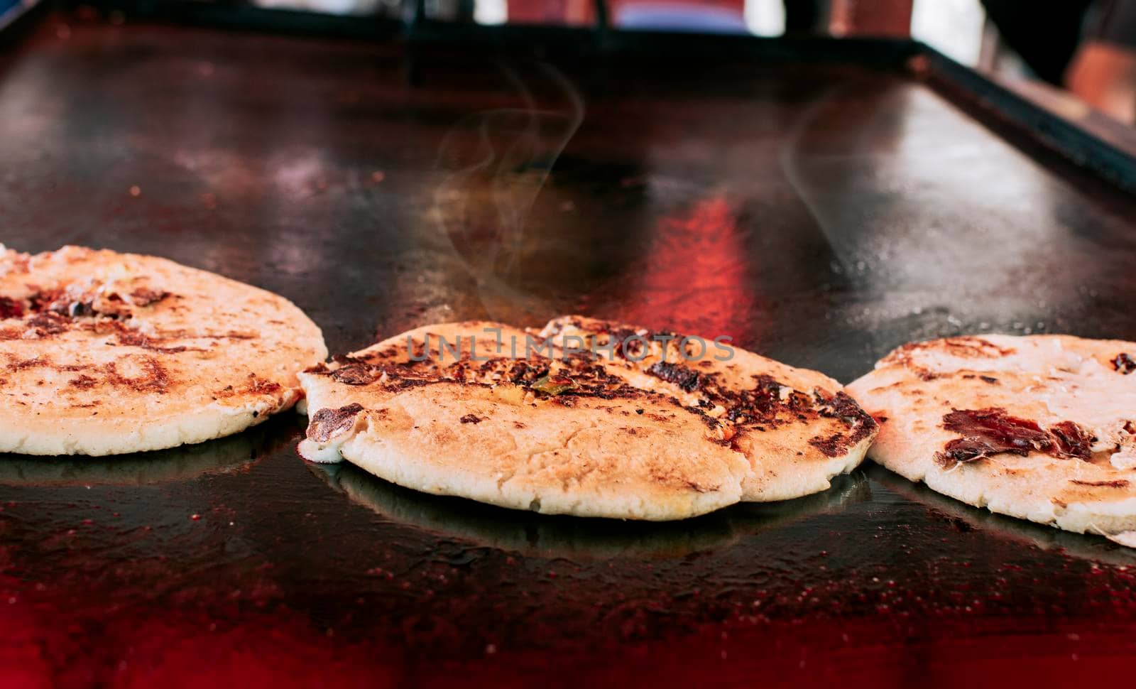 Three traditional Nicaraguan pupusas with melted grilled cheese, Traditional cheese pupusas on the grill, Close up of traditional handmade pupusas on the grill.