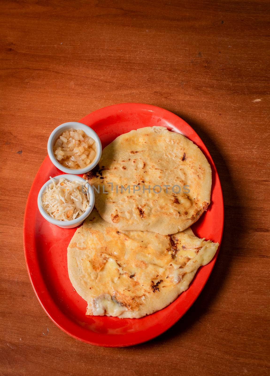 Closeup of Nicaraguan pupusas served on wooden table. Delicious traditional Salvadoran Pupusas with melted cheese on wooden table. Traditional pupusas served on a wooden table by isaiphoto