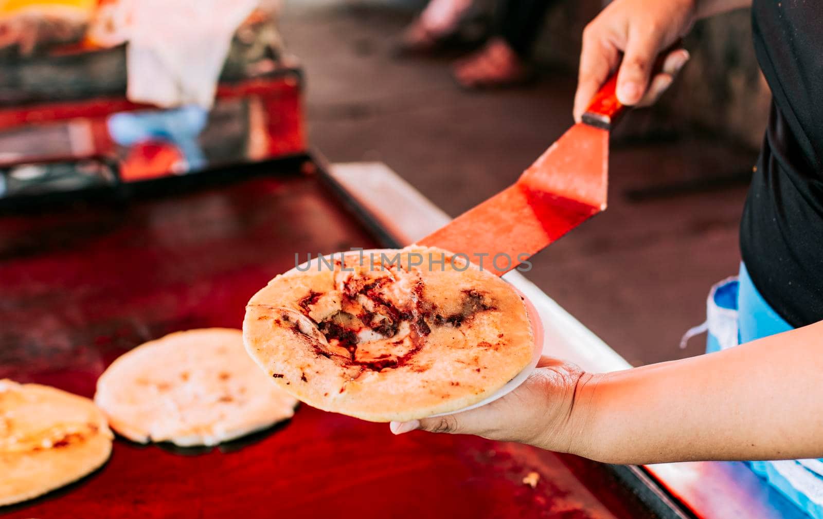 Hand holding a freshly made pupusa on a plate, Close up of traditional pupusa served on a plate. Traditional Salvadoran pupusas freshly made with melted cheese by isaiphoto
