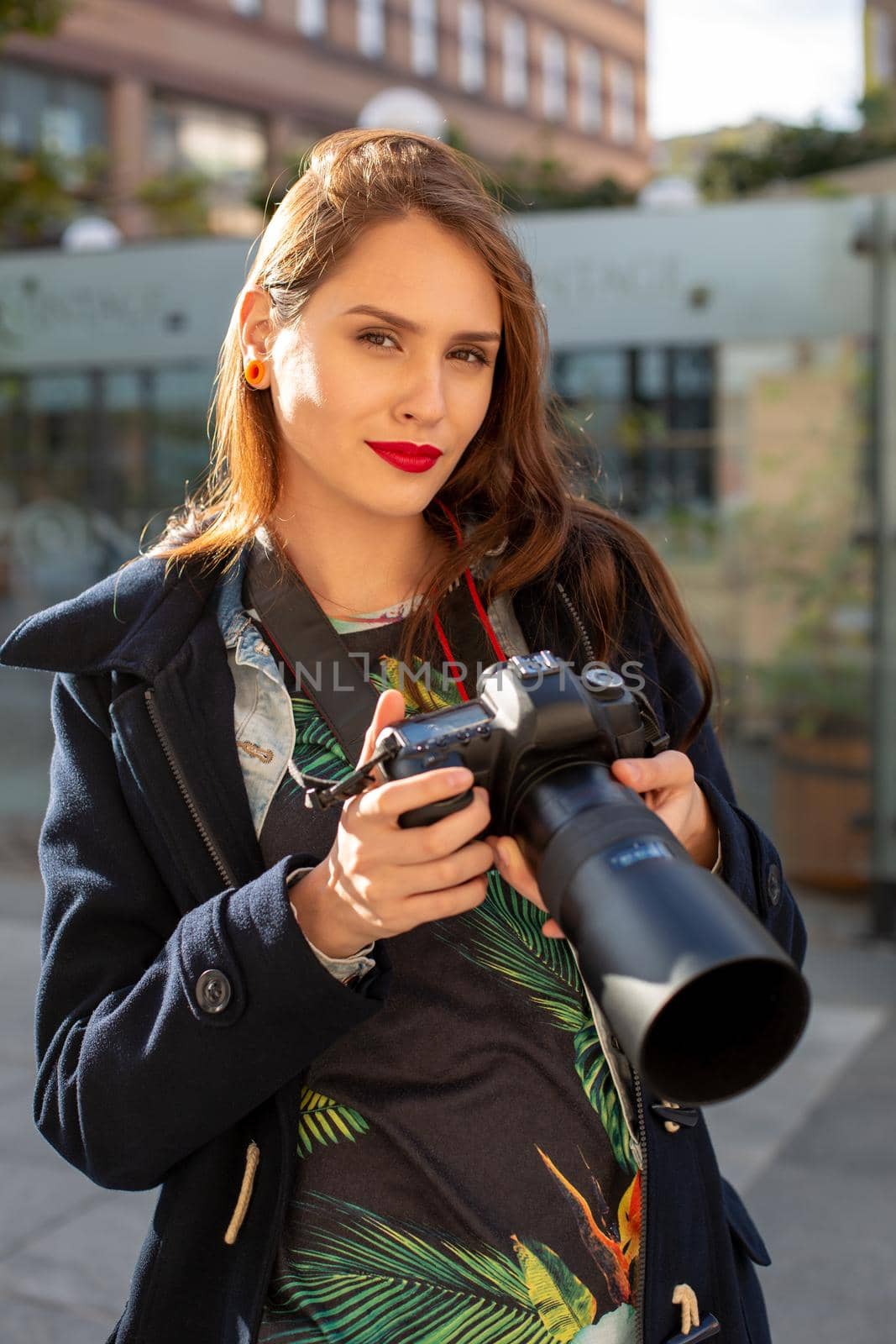 Attractive tourist woman photographer with camera, outdoor in city street. Gorgeous happy caucasian female in casual hipster clothes