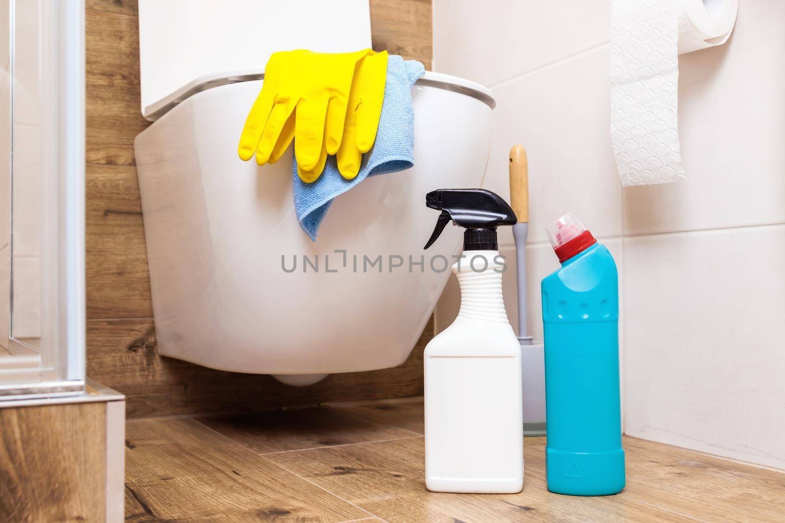 Close up white clean bottle and blue. Mockup, template for label design, cleaning product logo. Background, beautiful bathroom, toilet. Objects stand on a wooden floor. Cleaning equipment.