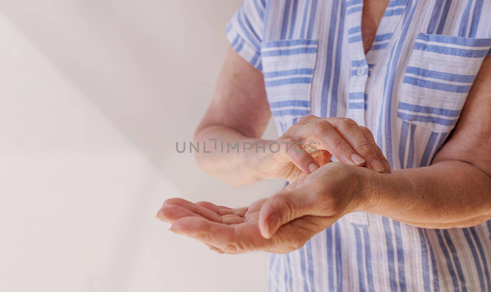 Close-up of an old woman's hands measuring her pulse. The concept of heart disease, coronary disease, high or low blood pressure. The medicine. Home conditions
