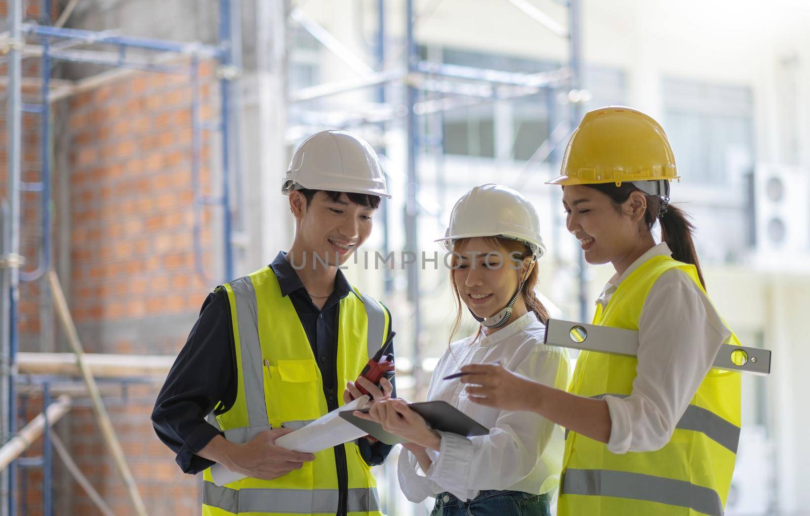 Professional Construction and Engineer team Working on workplace. Professional black architect and construction worker working look at blueprint plan on site. by wichayada