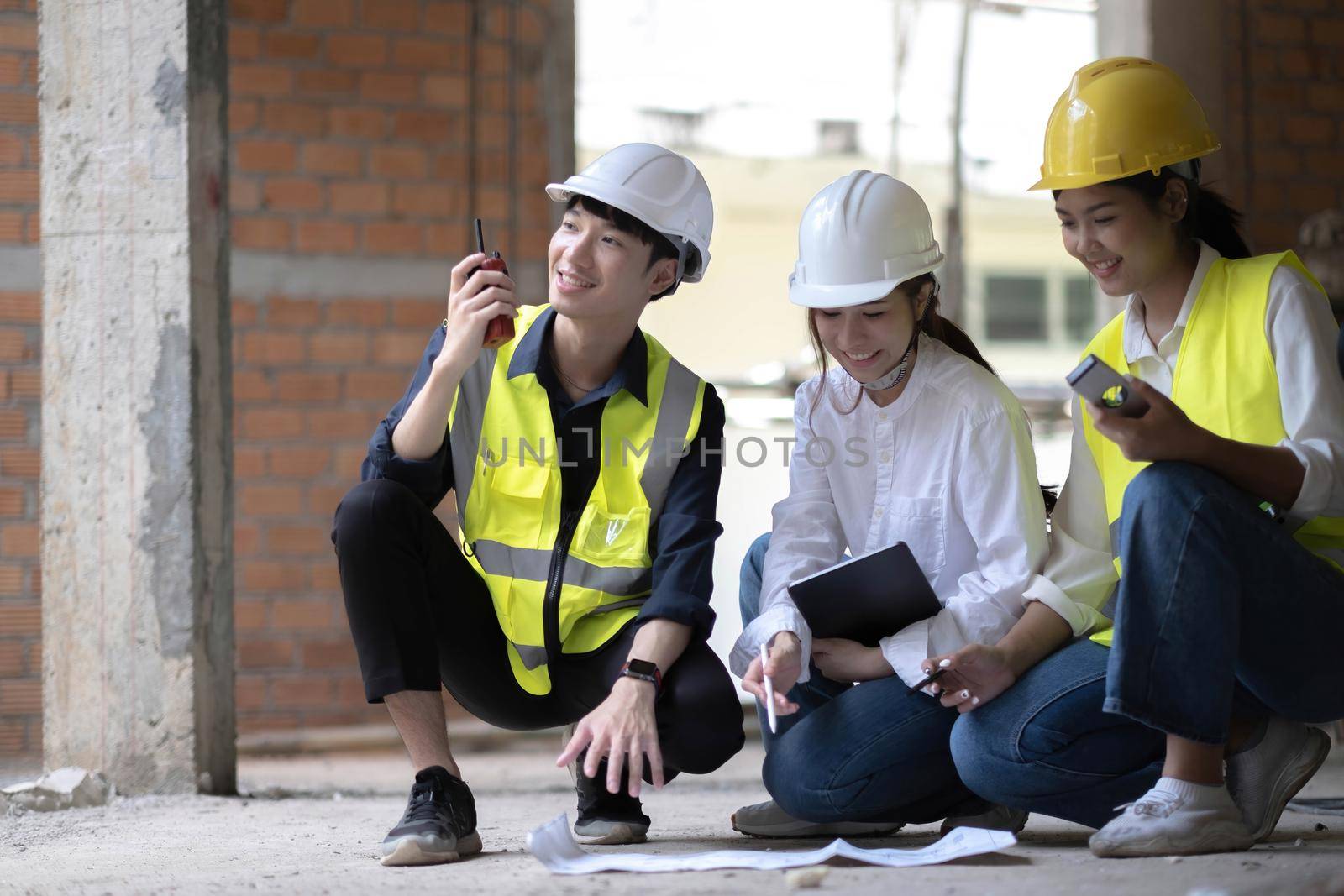 Professional Construction and Engineer team Working on workplace. Professional black architect and construction worker working look at blueprint plan on site. by wichayada