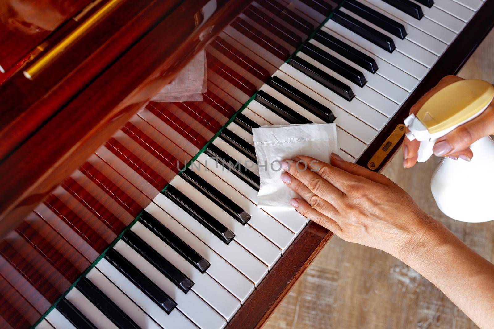 The girl wipes the piano with a special tool for the piano. hands close up by Ramanouskaya