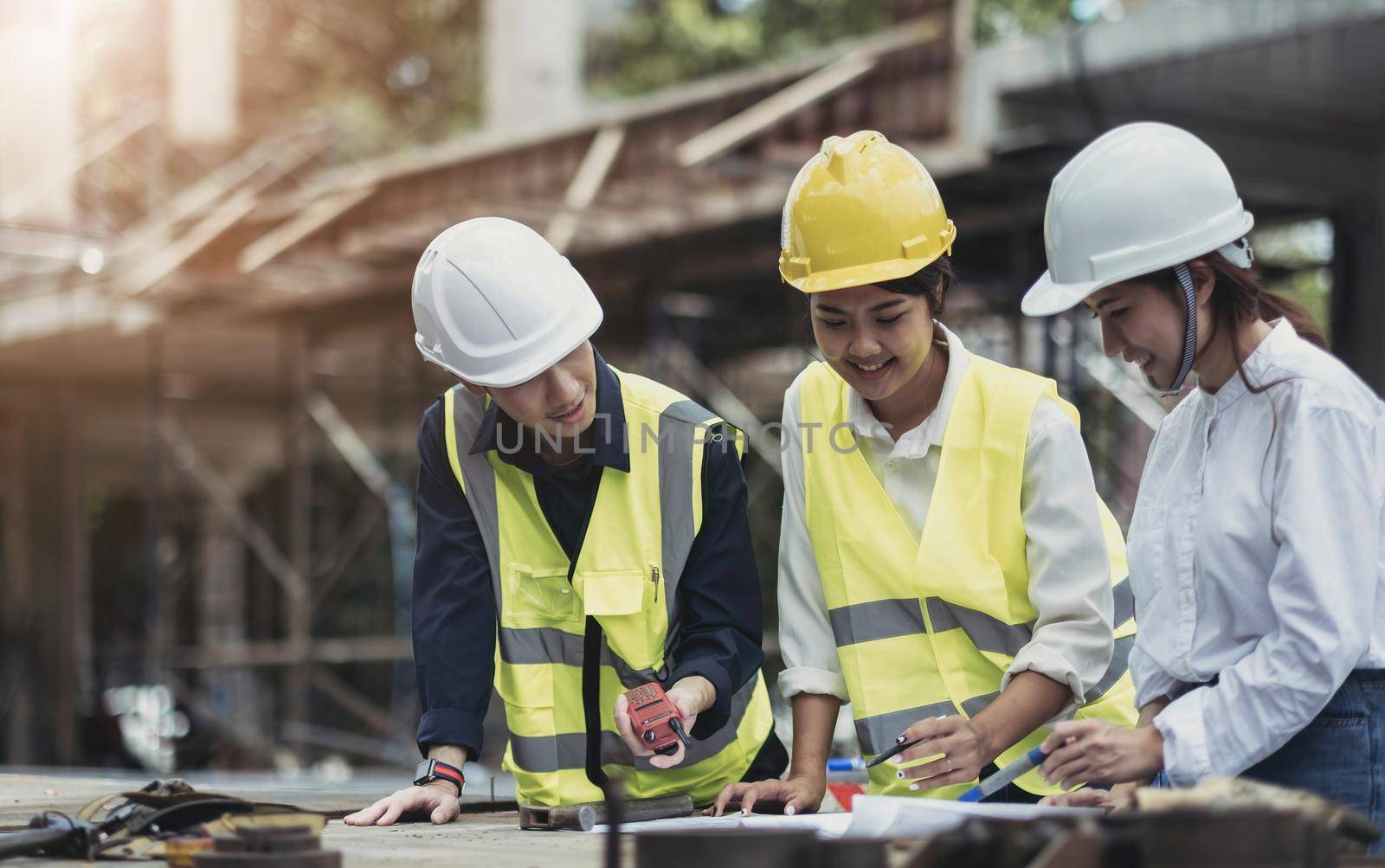 Three experts inspect commercial building construction sites, industrial buildings real estate projects with civil engineers, investors use laptops in background home, concrete formwork framing. by wichayada