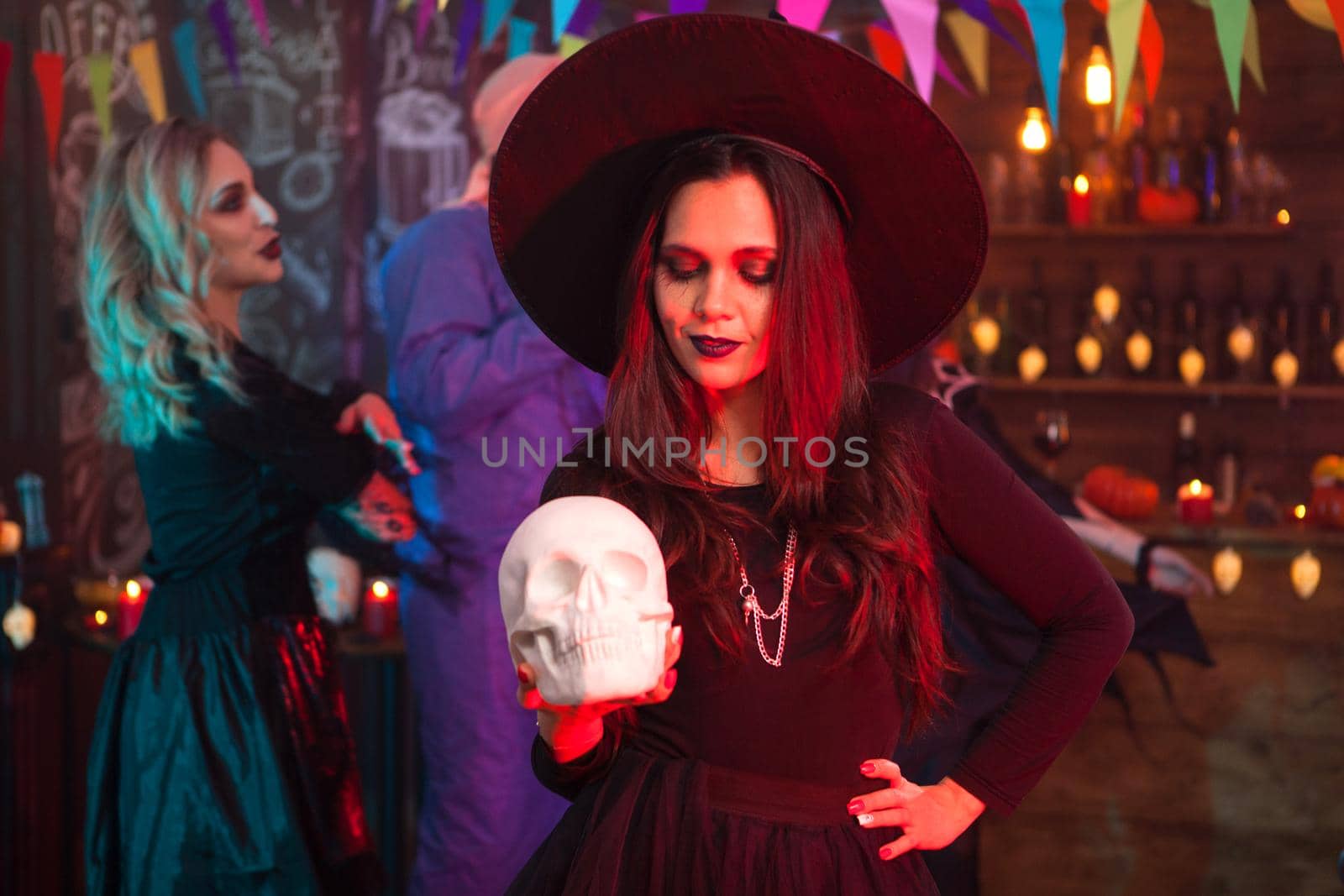 Thoughtful young woman in halloween costume looking at her human skull. Halloween costume.