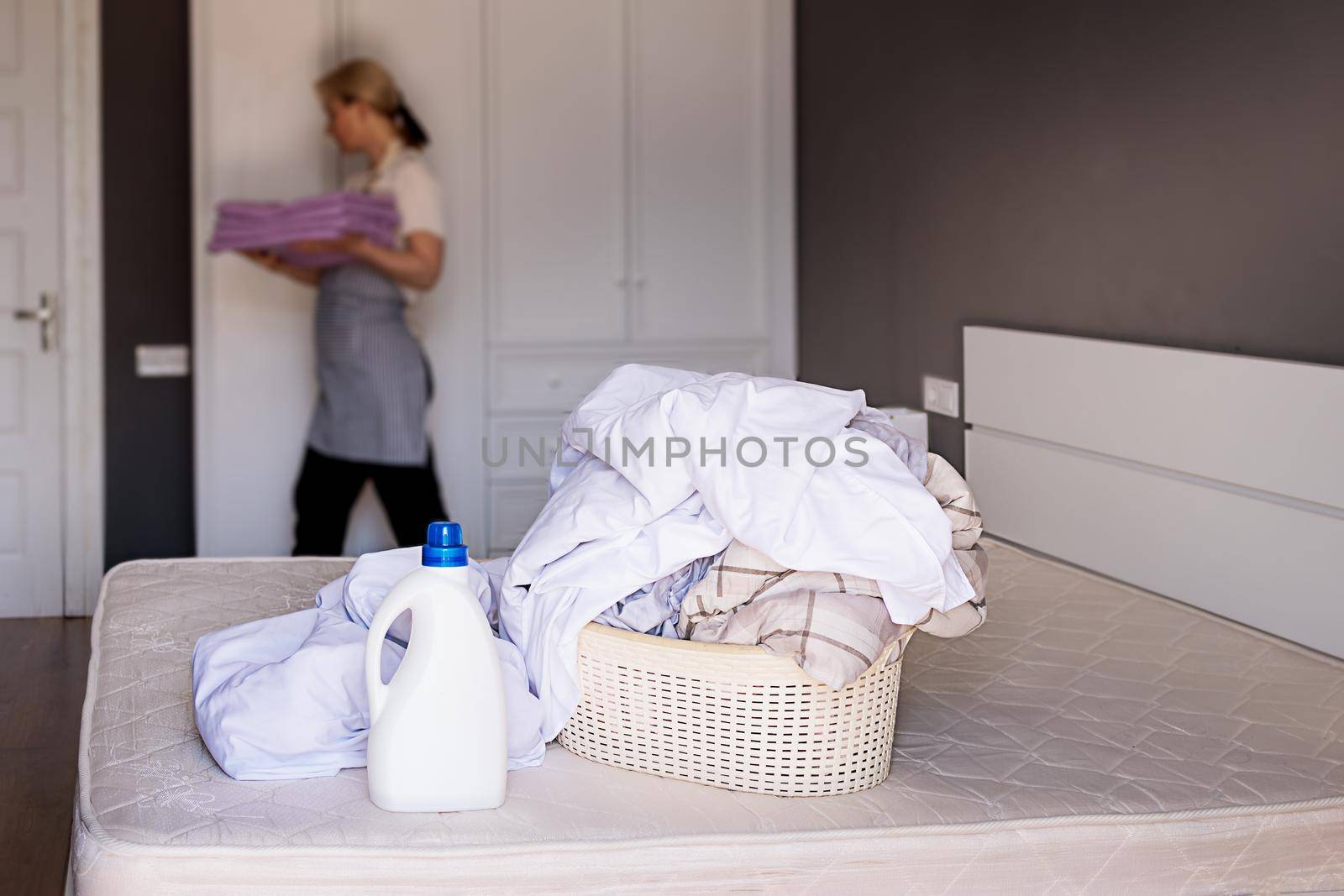 Staff cleans the hotel room, changes bed linen. Liquid laundry detergent mockup by Ramanouskaya