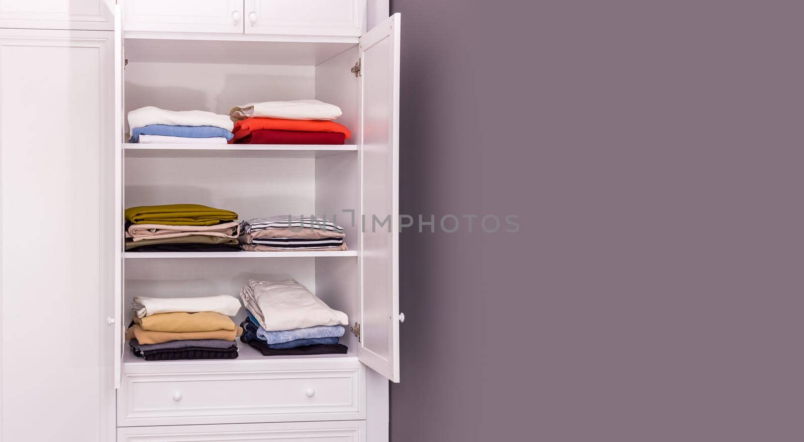 Close-up, a large white closet in which things are neatly stacked in piles. Copy paste space for design. The concept of order, organization of space, mental health. All on the shelves