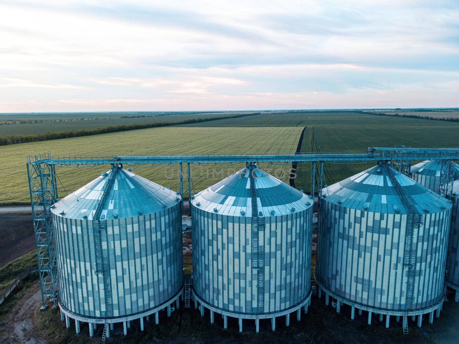 Grain elevator. Metal grain elevator in agricultural zone. Agriculture storage for harvest. Grain silos on green nature background. Exterior of agricultural factory