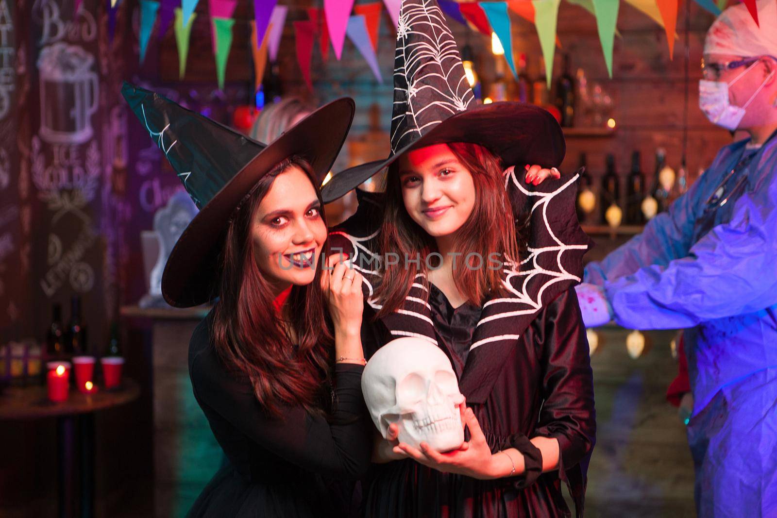 Attractive young witches looking into the camera at halloween party. Witches celebrating friendship.