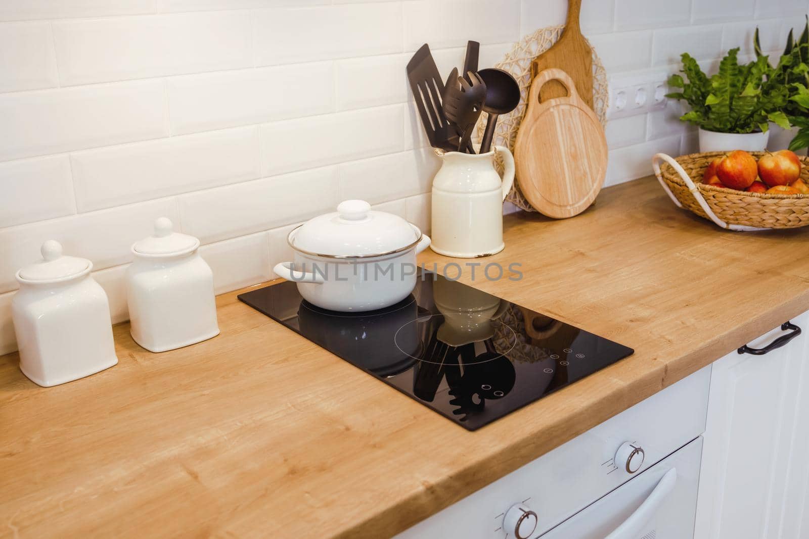 Mock-up with kitchen equipment Wooden table surface with induction cooker and kitchen utensils, in the rays of sunlight. Healthy food and natural products concept, copy paste
