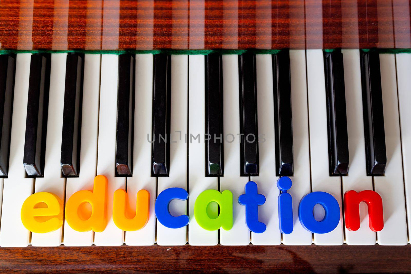 Poster with the word education. The letters are laid out on the piano close-up by Ramanouskaya