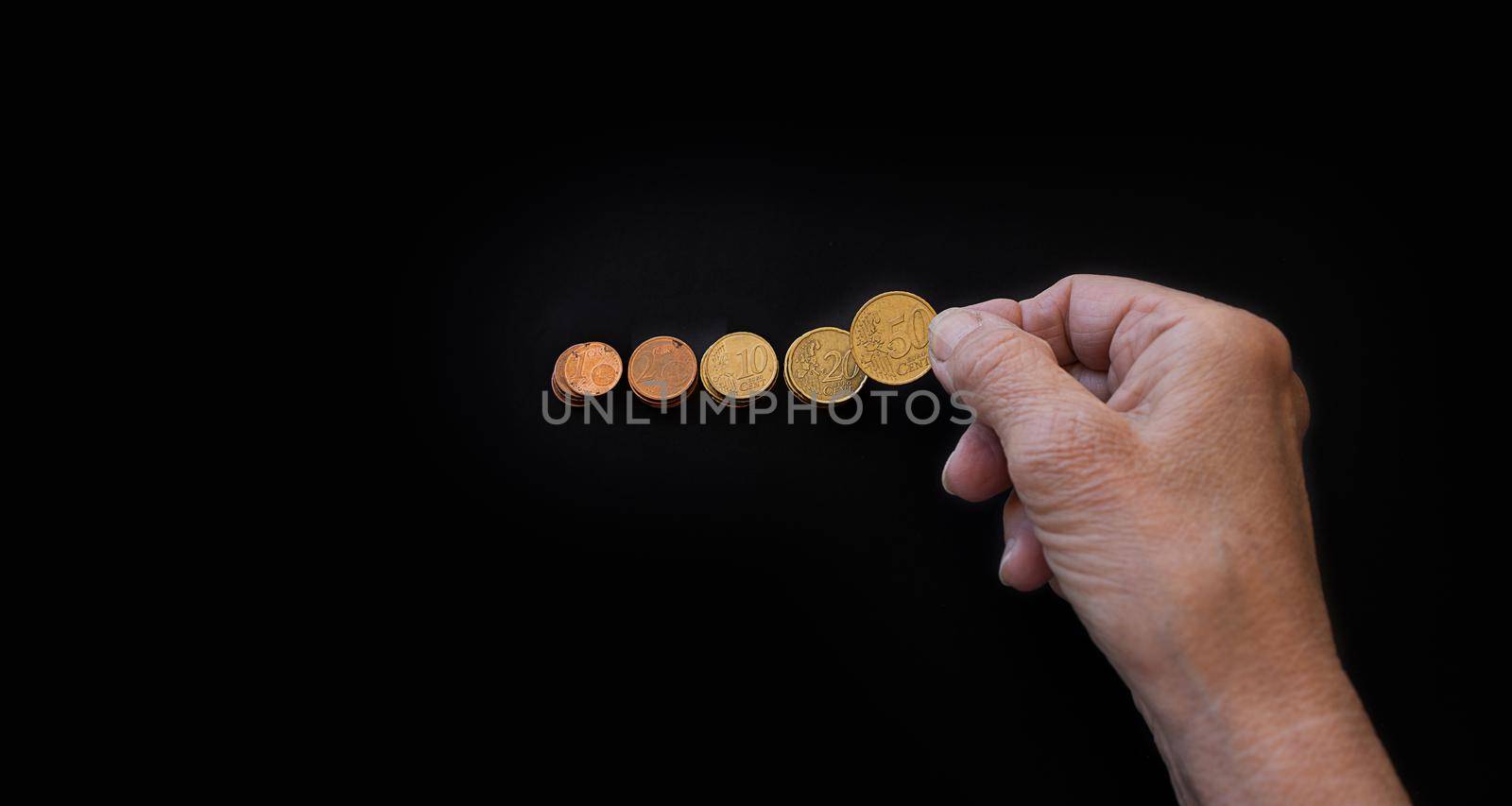 close-up, the hand of an elderly woman lays out coins on a black background by Ramanouskaya