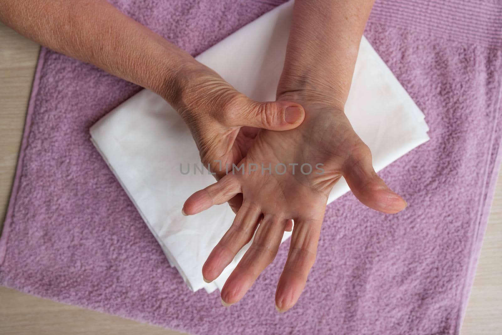 close-up hands of old woman with arthritis and wrinkles, give herself hand massage. Prevention of neurological diseases in elderly, concept of retirement, healthy lifestyle, proper nutrition