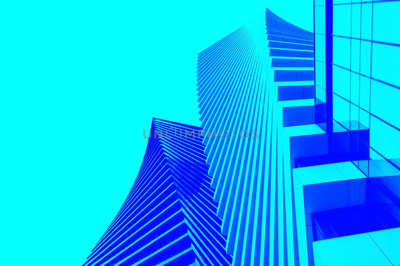 Wide angle abstract background view of a steel bright blue high-rise glass skyscraper commercial building. Concept of successful industrial architecture and office center building