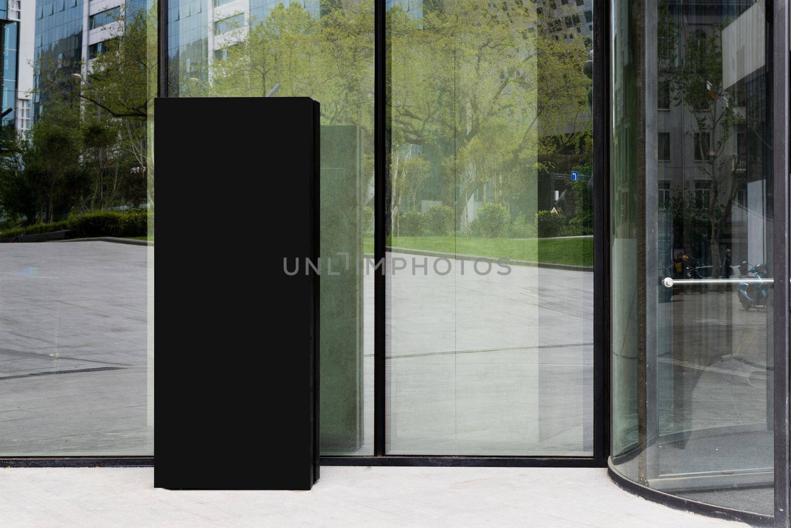 mockup of a street sign for a restaurant or hotel near large glass doors. Signboard for business building, hotel, restaurant, residential complex. Large glass showcase reflecting the city