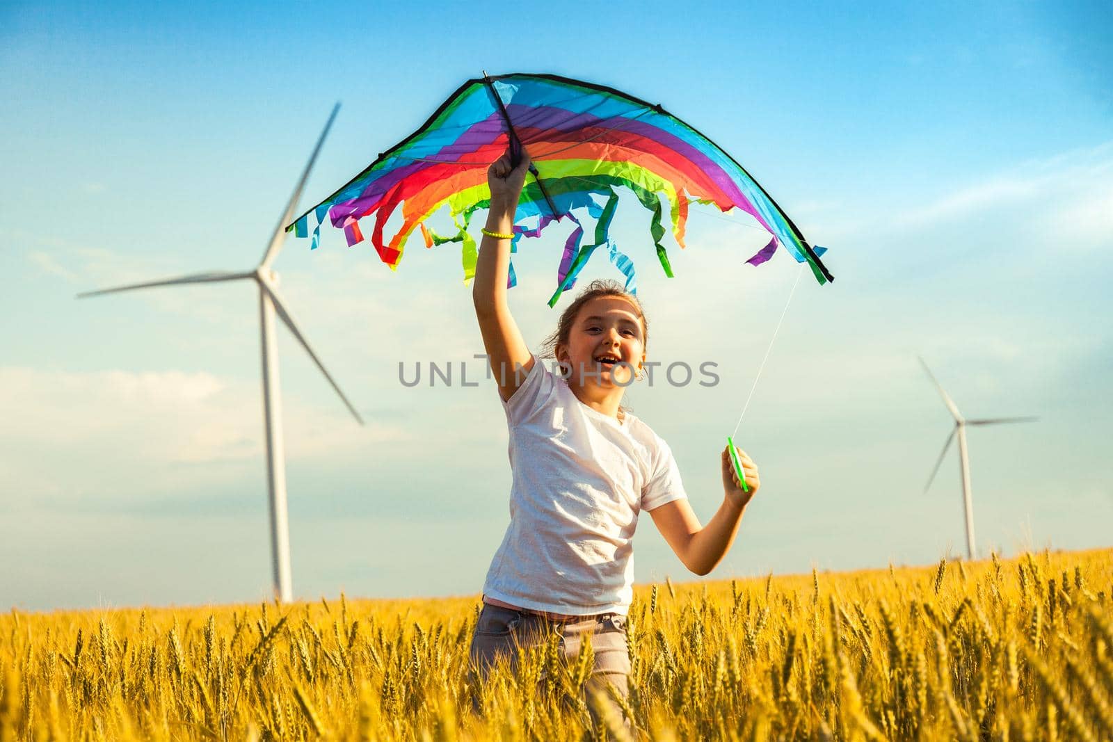 Happy Little girl running in a wheat field with a kite in the summer. Well-planned and active weekend. Happy childhood.