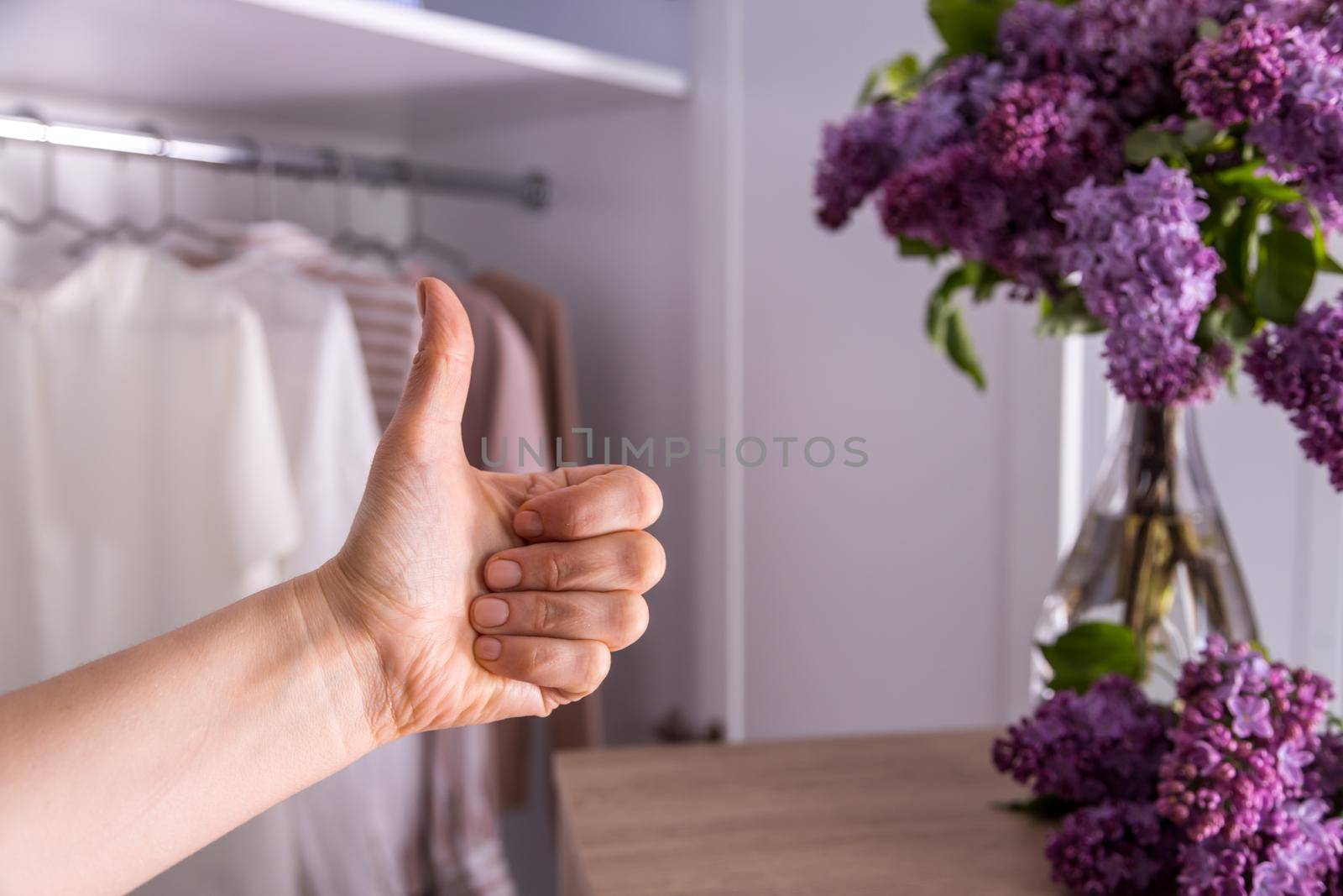 Mock-up, against the background of a closet with clean clothes, a hand shows like by Ramanouskaya