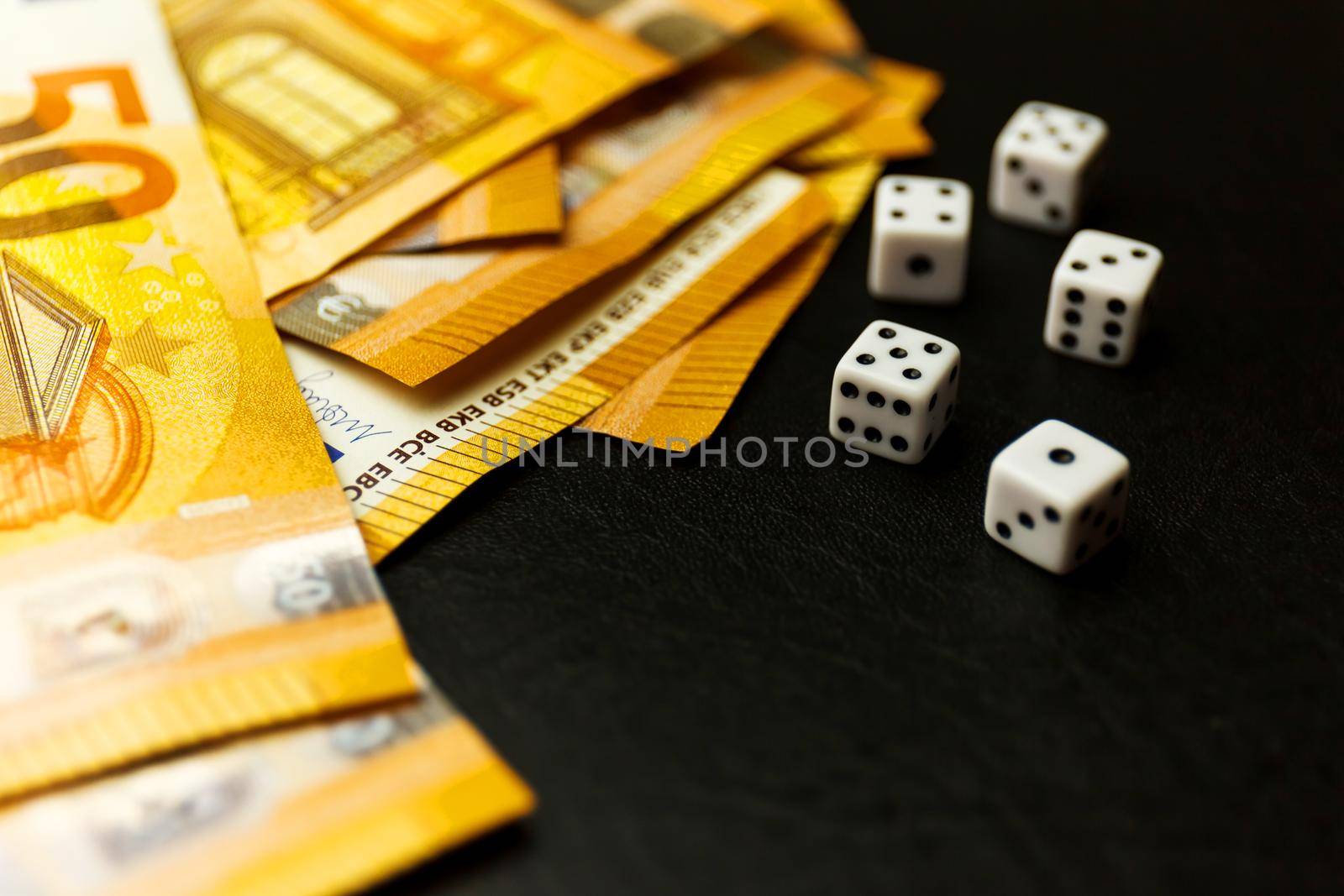 White Gaming dice and money on dark table. by InnaVlasova