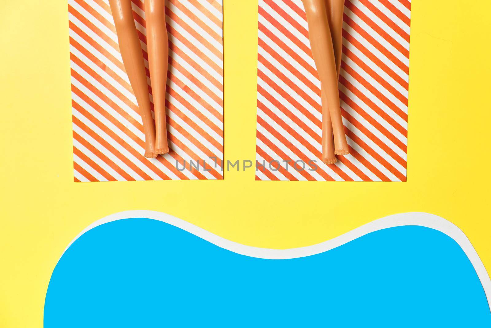 Summer vacation layout with doll legs on beach towels, flat pool, beach, yellow background. by InnaVlasova