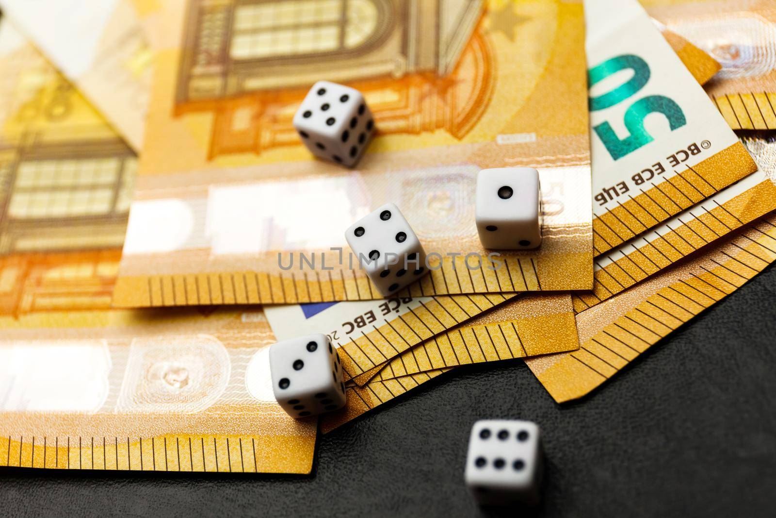 White Gaming dice and money on dark table. by InnaVlasova