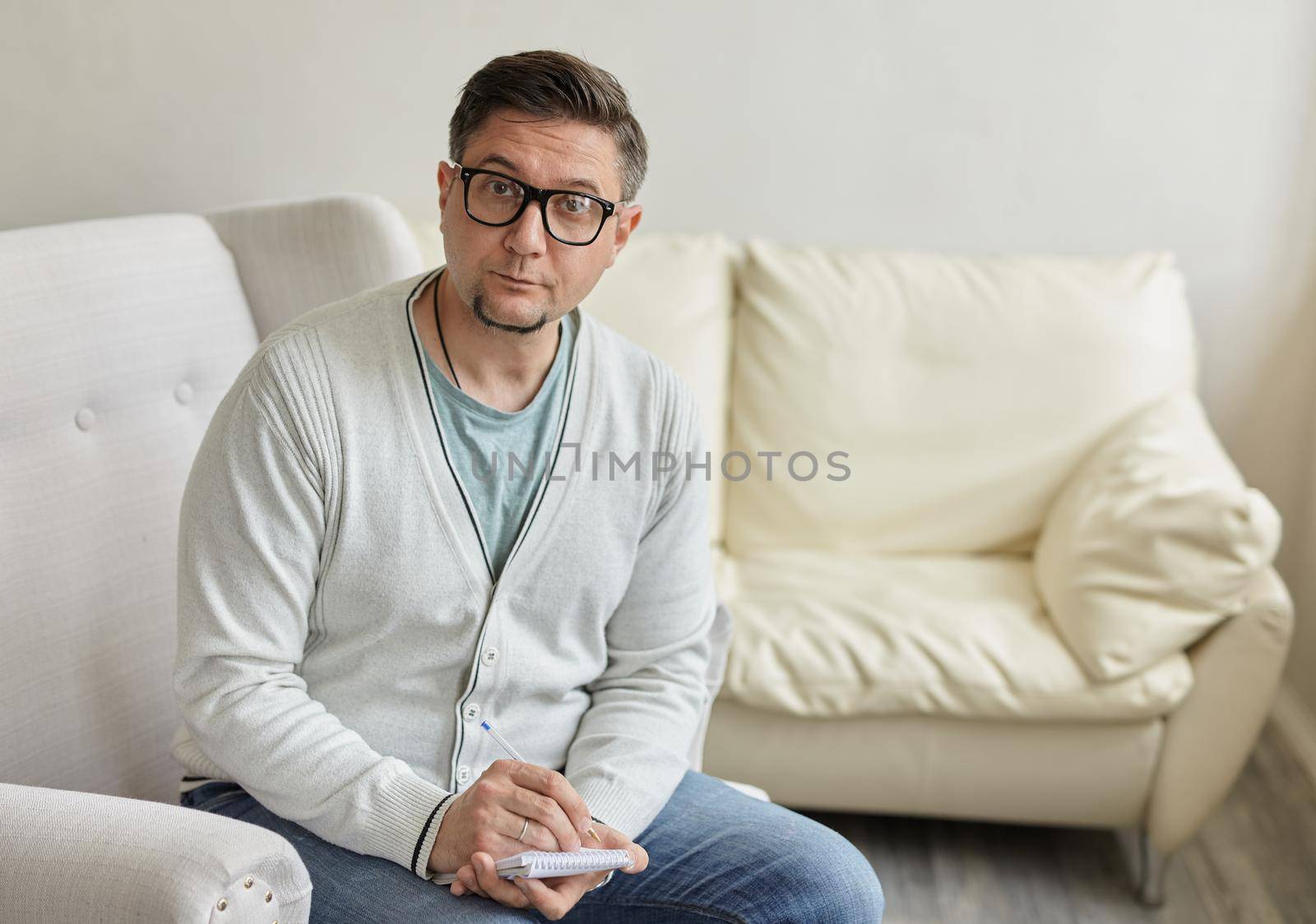 Waiting for patient. Friendly psychologist sitting with clipboard, in office, empty space